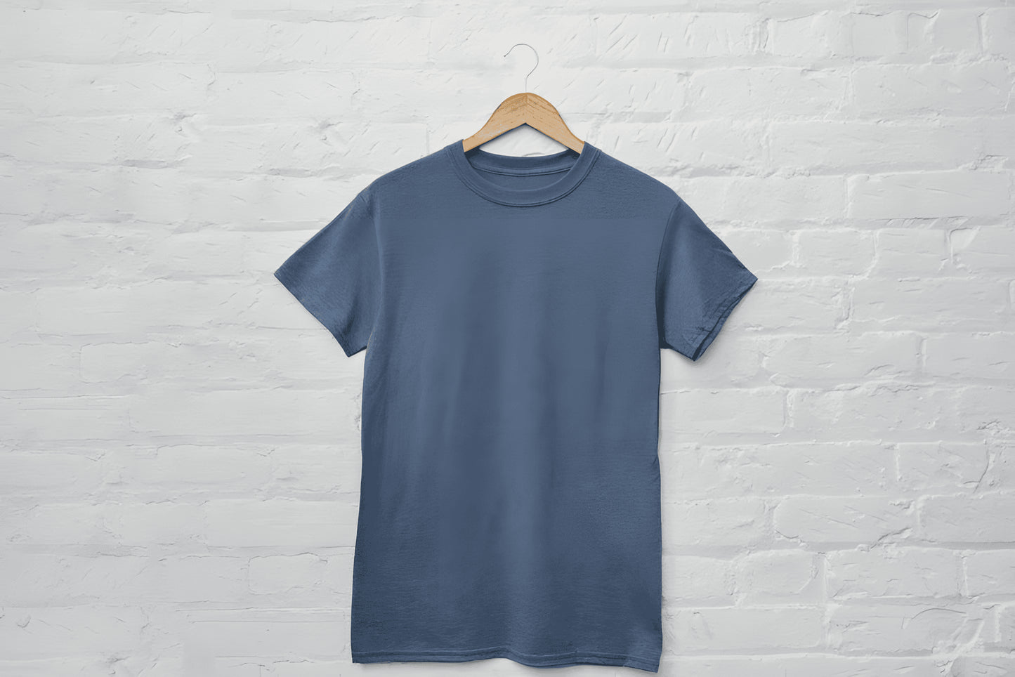 Blue t-shirt on a hanger against a white brick wall