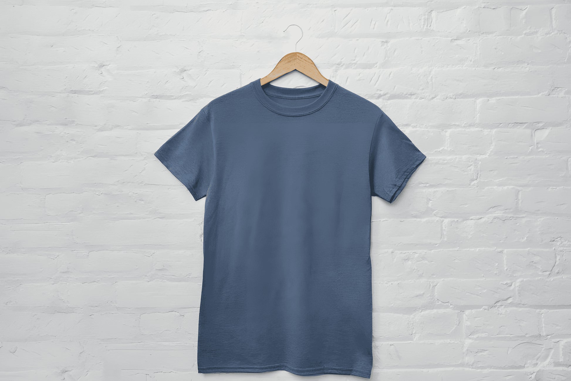 Blue t-shirt on a hanger against a white brick wall